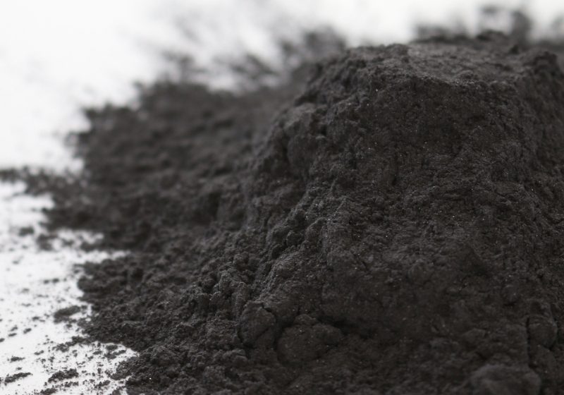 A pile of graphite powder is placed on a flat surface.