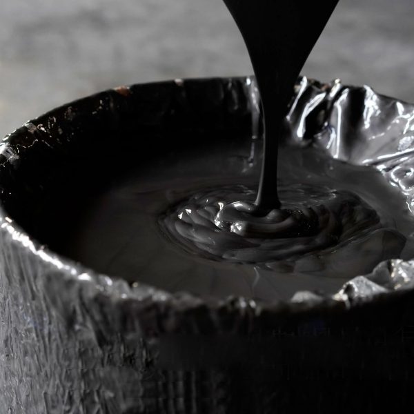 Graphite emulsion is poured into a barrel.